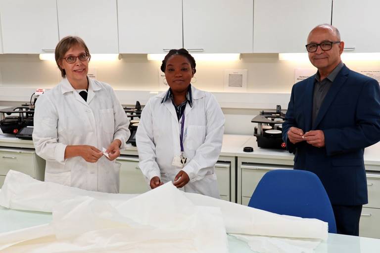 Two women and a man standing in a textile laboratory.