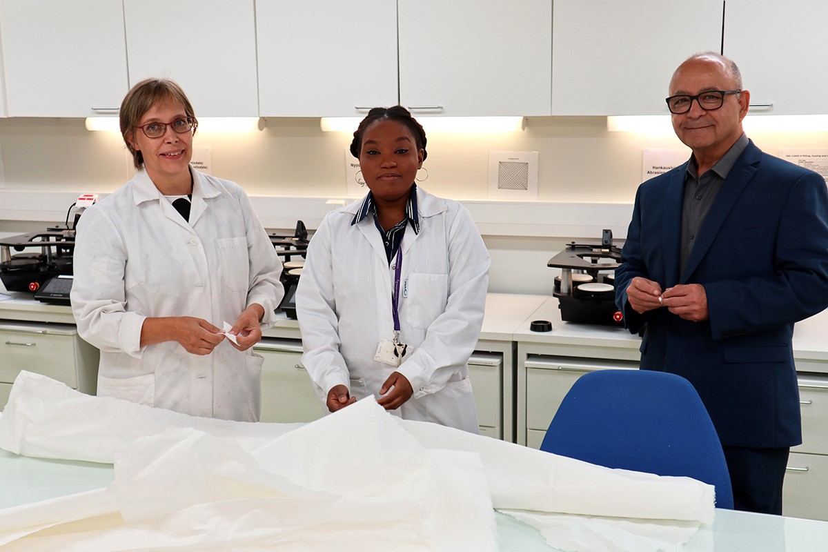 Two women and a man standing in a textile laboratory.