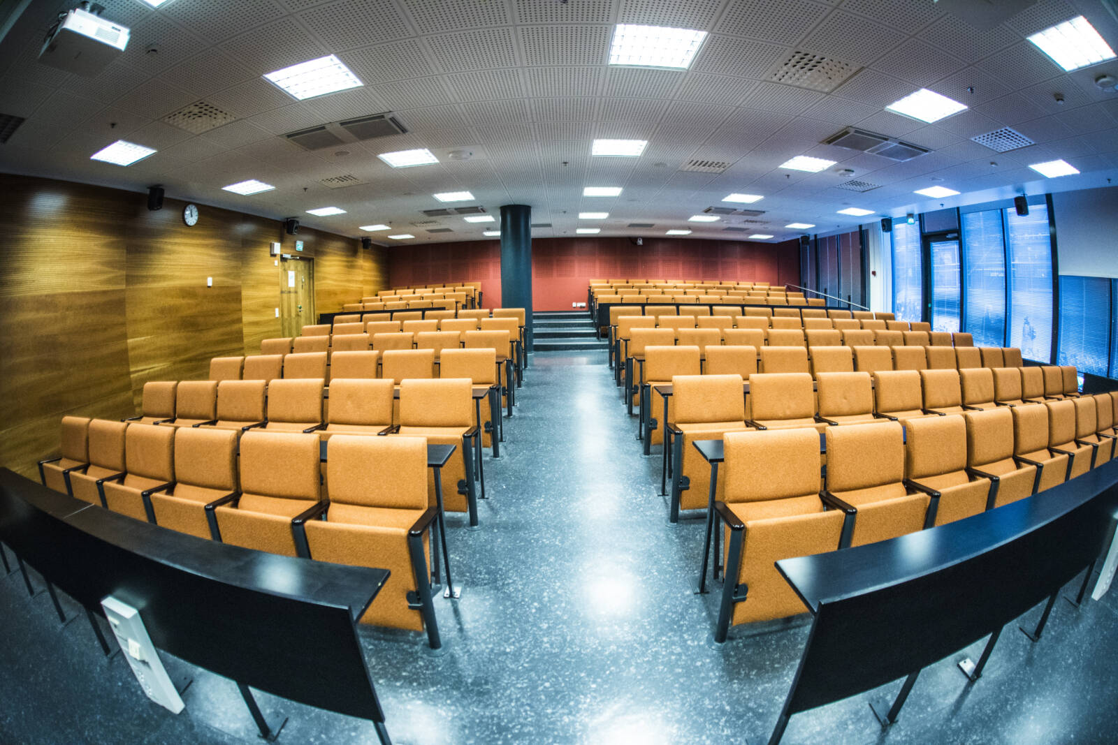 Tyhjän luentosalin keskellä on käytävä, jonka molemmilla puolilla on istuimia.