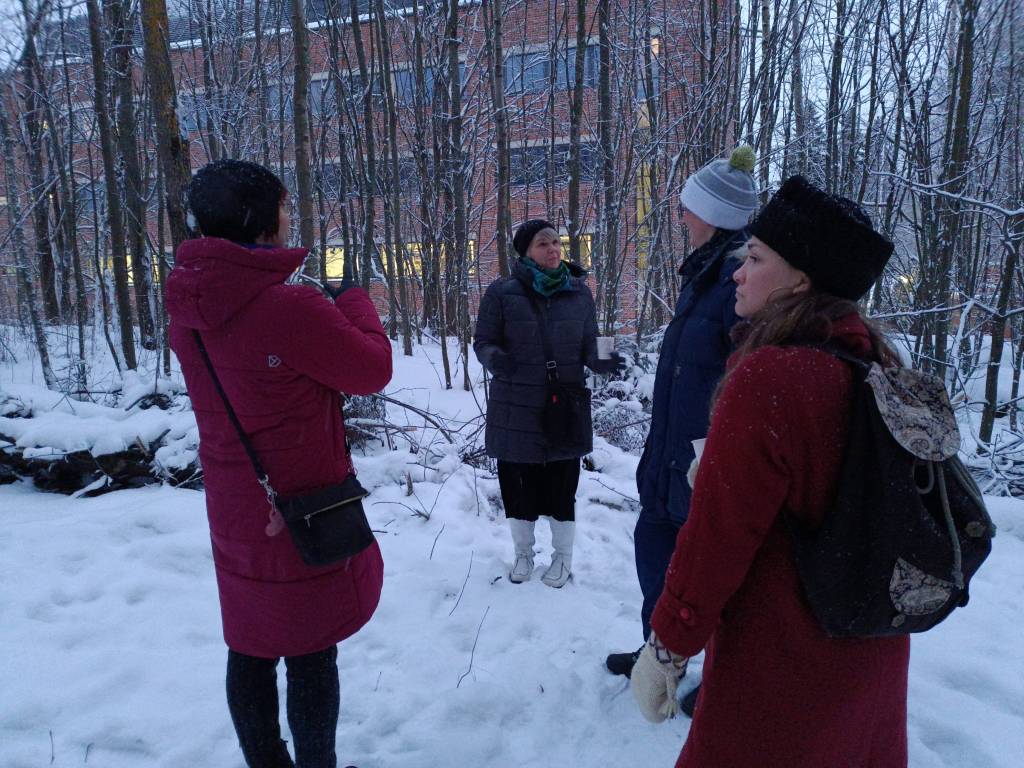 Neljä ihmistä aukiolla Metsälämpäreellä