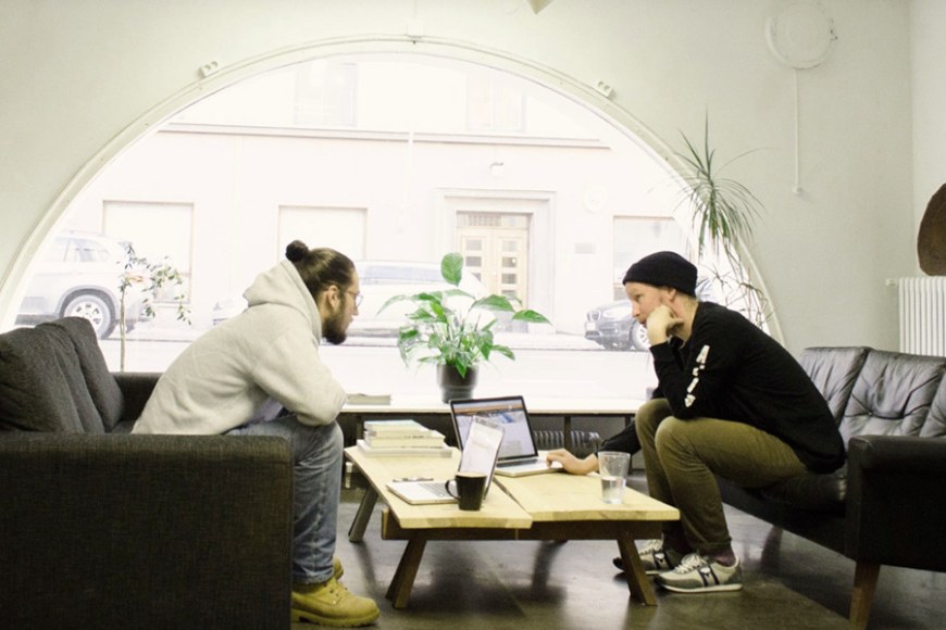 Kaksi henkilöä keskustelemassa työtilassa.