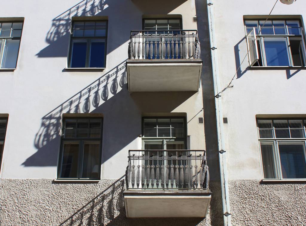 Aurinko heittää parvekkeiden varjoja vaalealle rappauspinnalle.