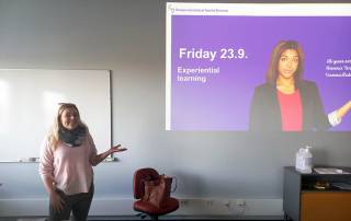 Light-haired woman presenting a powerpoint slide. 