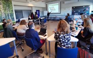People in a class room listening to a presentation. 