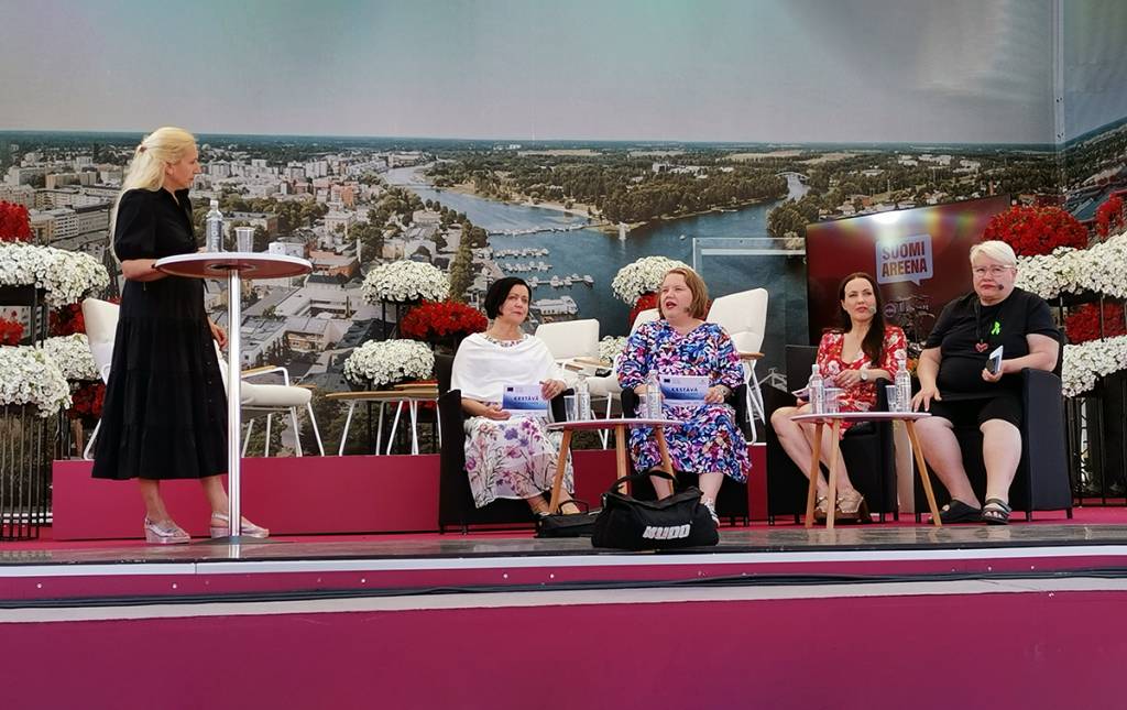 Viisi naista ulkona esiintymislavalla. 