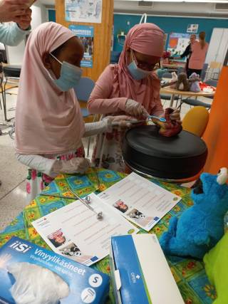 Kaksi lasta pesee ja tutkii dinosauruksen hampaita.