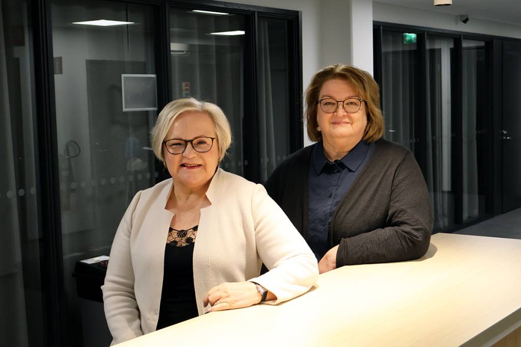 Kaksi naista nojaa neuvottelupöytään.