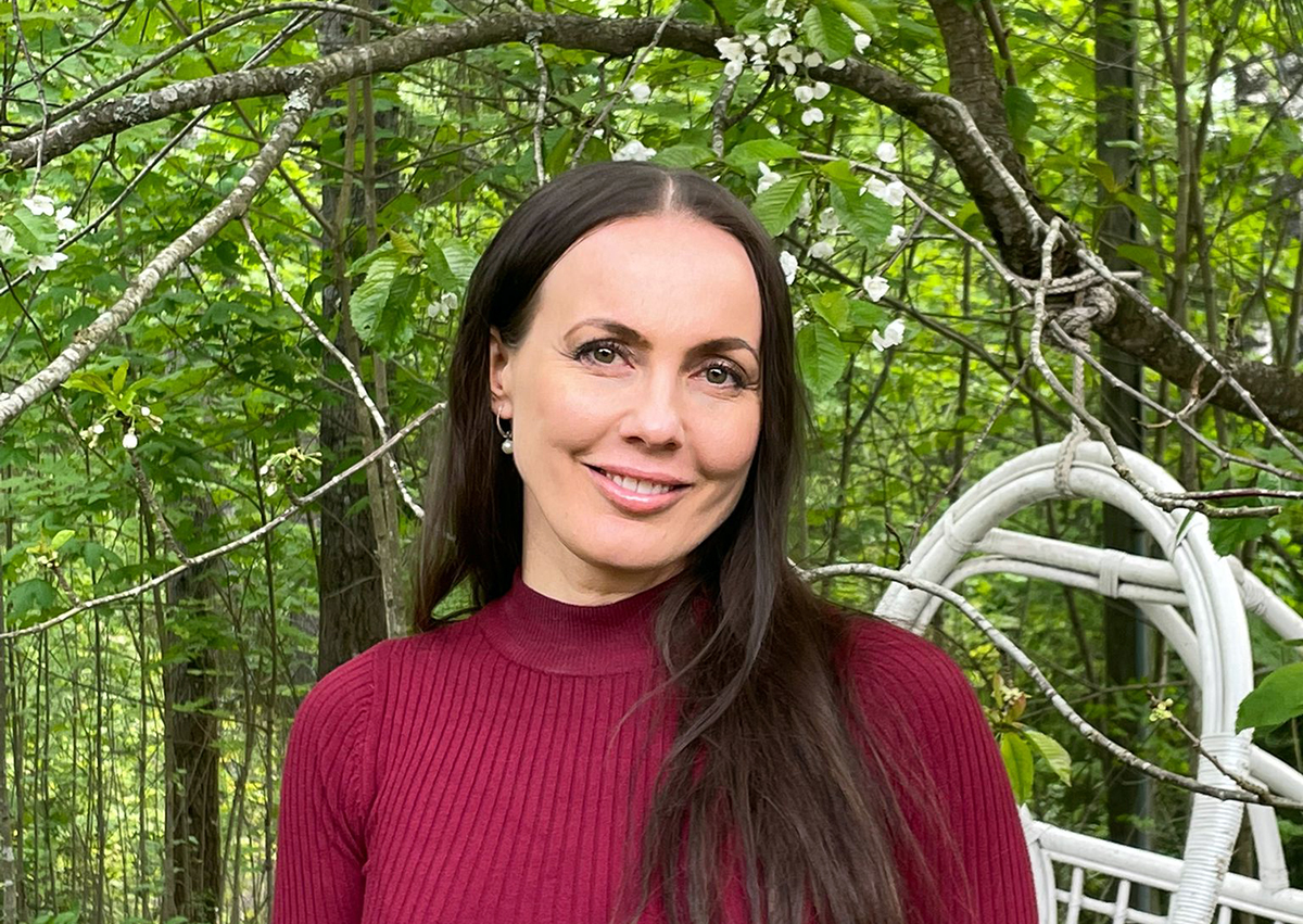 Hymyilevä tummatukkainen nainen viininpunaisessa puserossa.