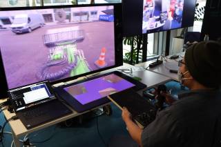 A person looking at 3D displays and remotely operating a vehicle.