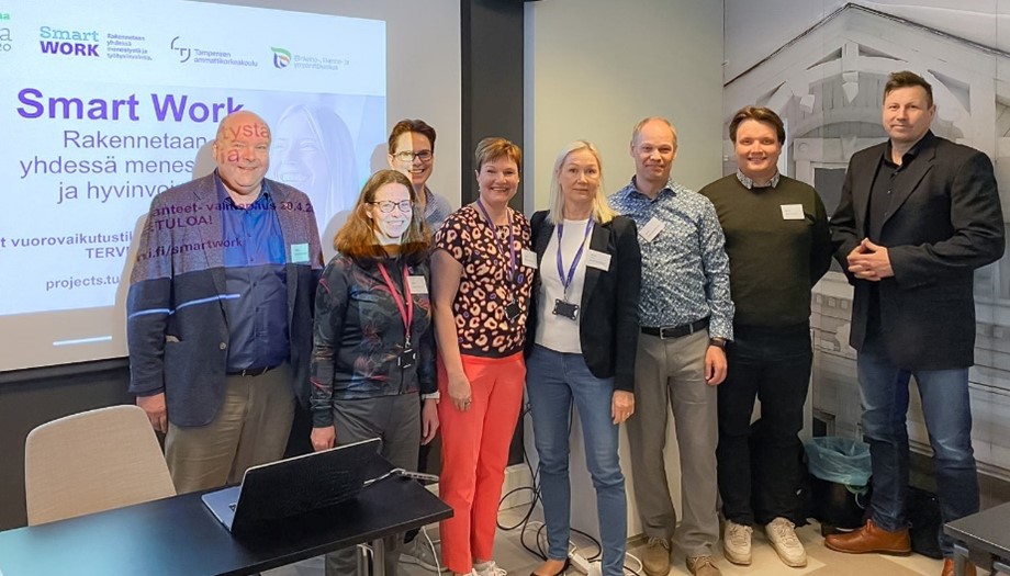 Petri Murtomäki, Pipsa Tuominen, projektipäällikkö Piia Tarnanen, Maija Koivunen, Tiina Wickman-Viitala, Veijo Hämäläinen ja Ville Parkkila sekä valmentaja Harri Gustafsberg seisovat vierekkäin luokkahuoneessa.