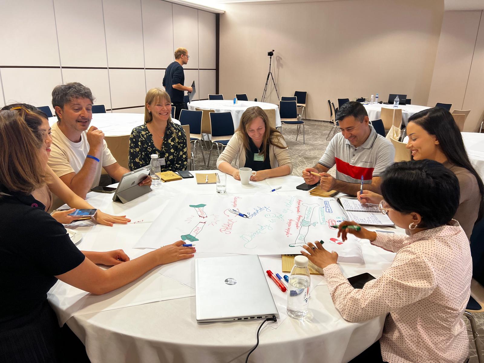 Ryhmä ihmisiä pöydän ympärillä.