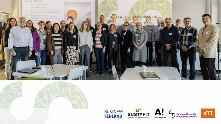 Group of smiling people standing in a classroom.
