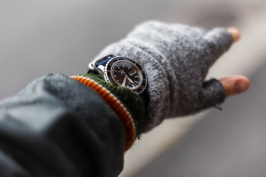 Talvivaatteisiin puettu ihmiskäsi, ranteessa näkyy kello.