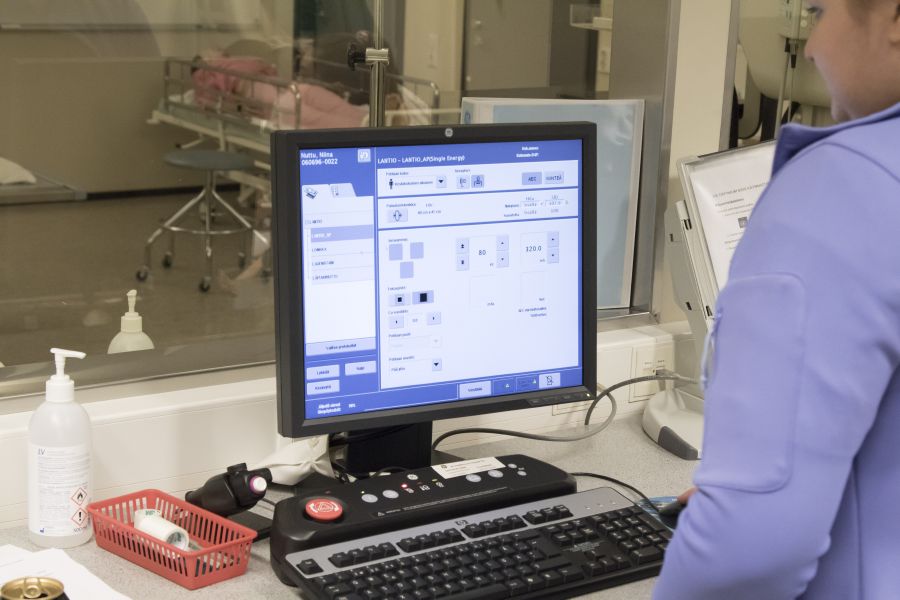 Mies tietokoneen näytön ääressä toimistoympäristössä.