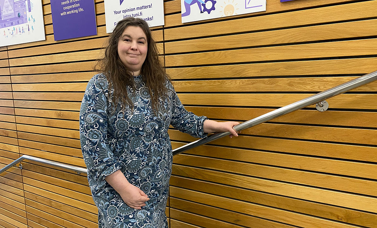 Tummatukkainen nainen rappusissa.