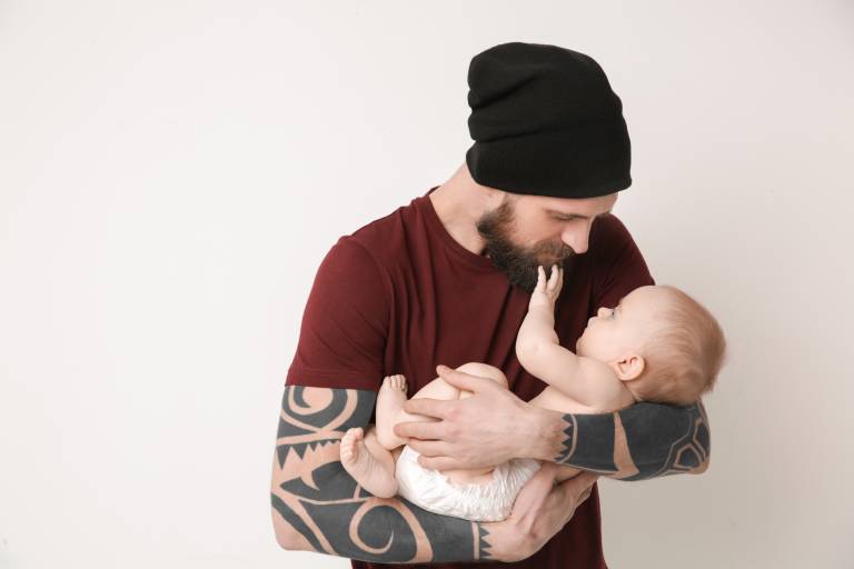 Isä pitää vauvaa sylissä.