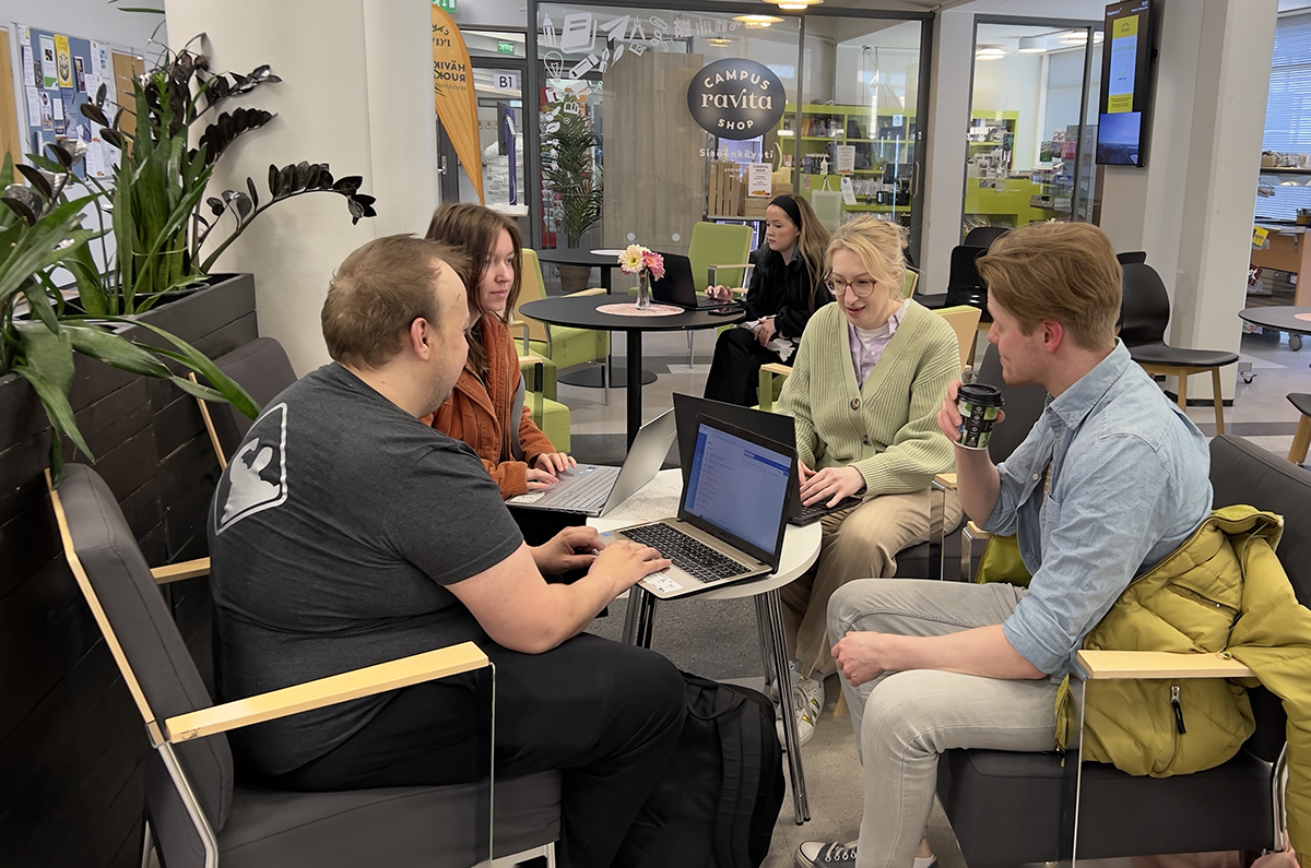 Young people gathered around cafeteria table.