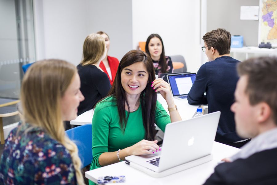 Iloisia opiskelijoita luokkahuoneessa.