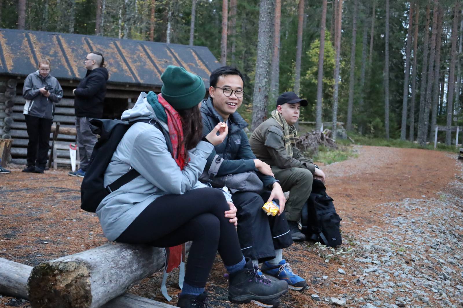 Ruskaretken osallistujia keskustelee iloisesti puunrungolla istuen