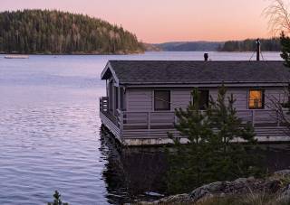 Moduulirakenteinen kelluva huoneisto auringonlaskun aikaan saaren rantavedessä.