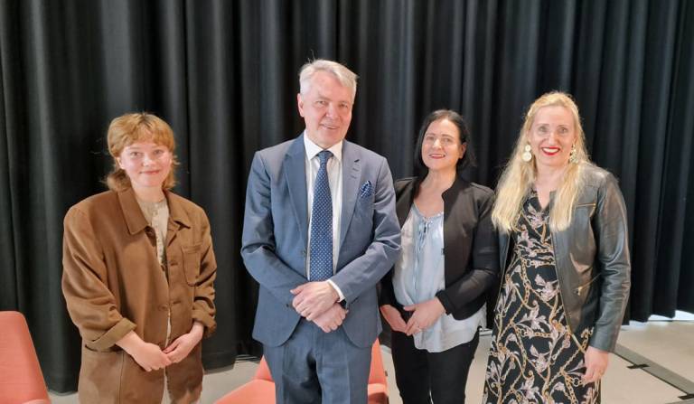 Neljä henkilöä seisomassa rinnatusten sisätiloissa.