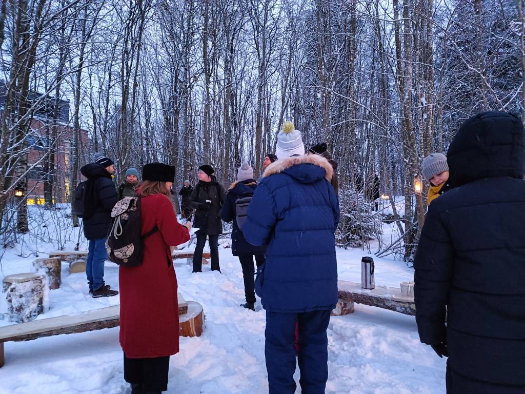 Ihmisiä Metsälämpäreen avajaisissa lumisessa metsässä