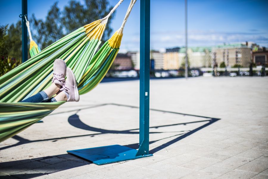 Hiekkakentällä riippumatto, jossa loikoilevan henkilön jalat näkyvissä.