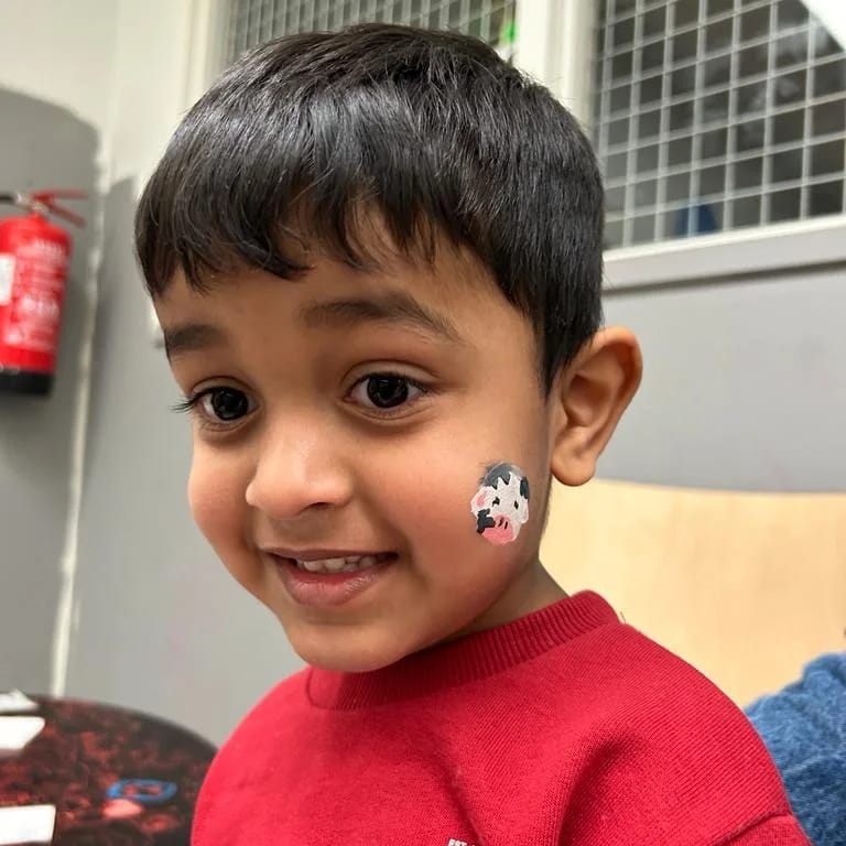 Iloinen lapsi, jolla kasvomaalaus poskessa.