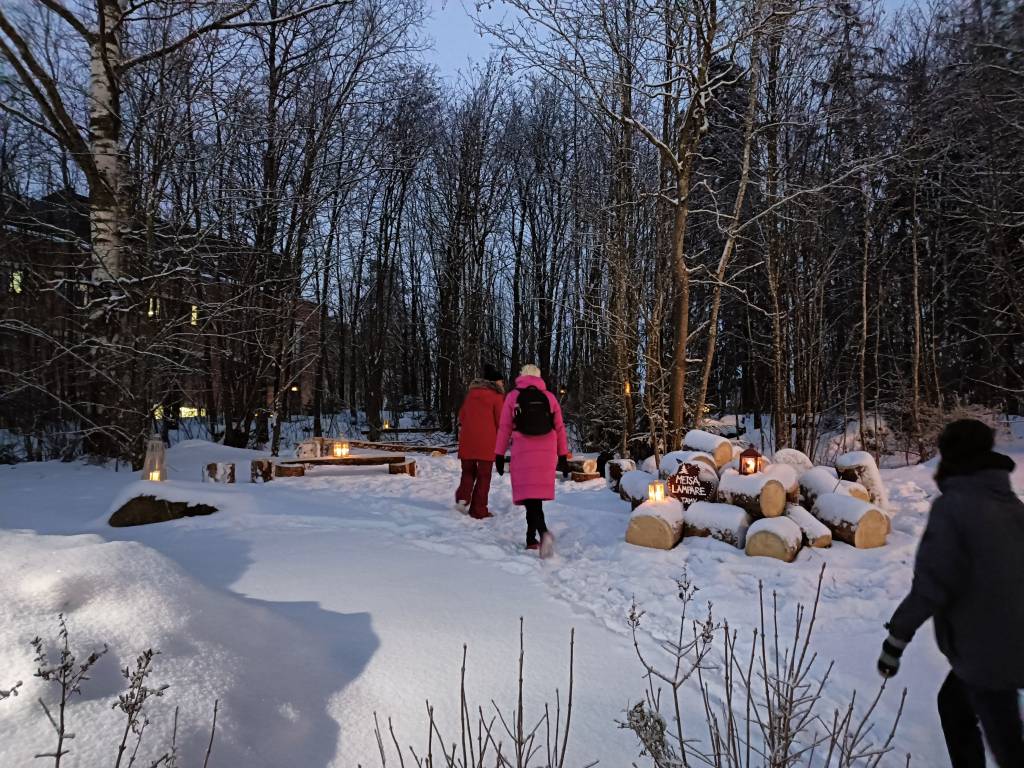 Muutama ihminen taivaltaa kohti lyhtypolkua Metsälämpäreellä