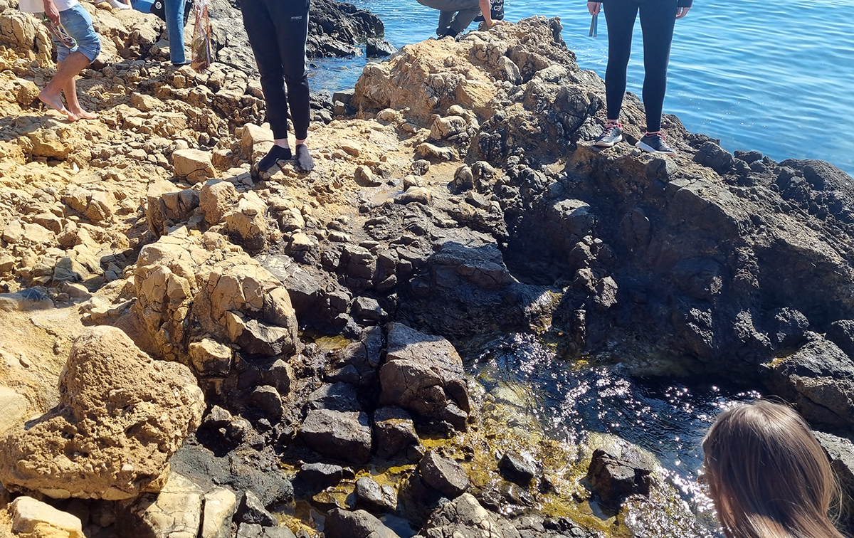 People walking at rocky beach.