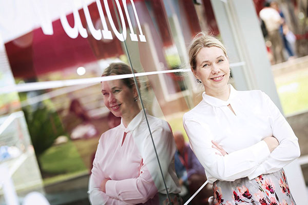 Hymyilevä nainen nojaa ikkunaan.