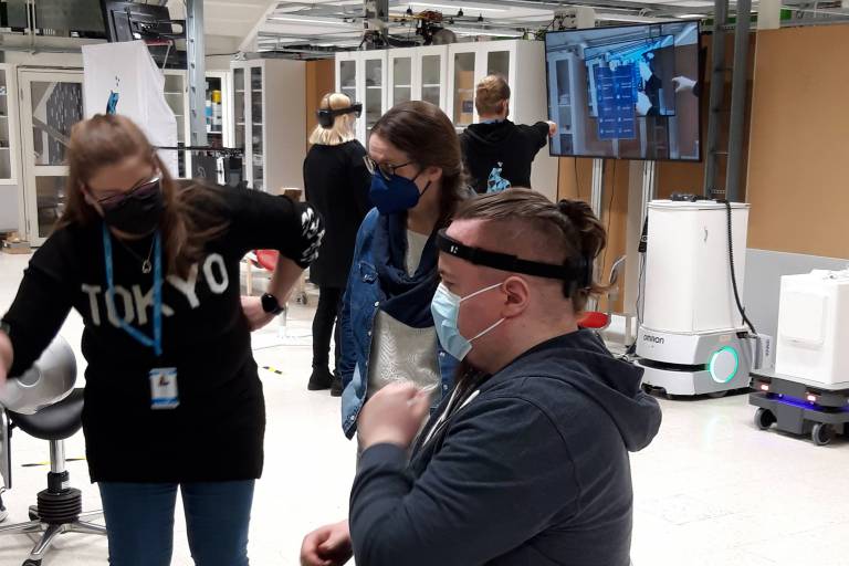 Nainen esittelee miehelle ja naiselle virtuaalilasien toimintaa.