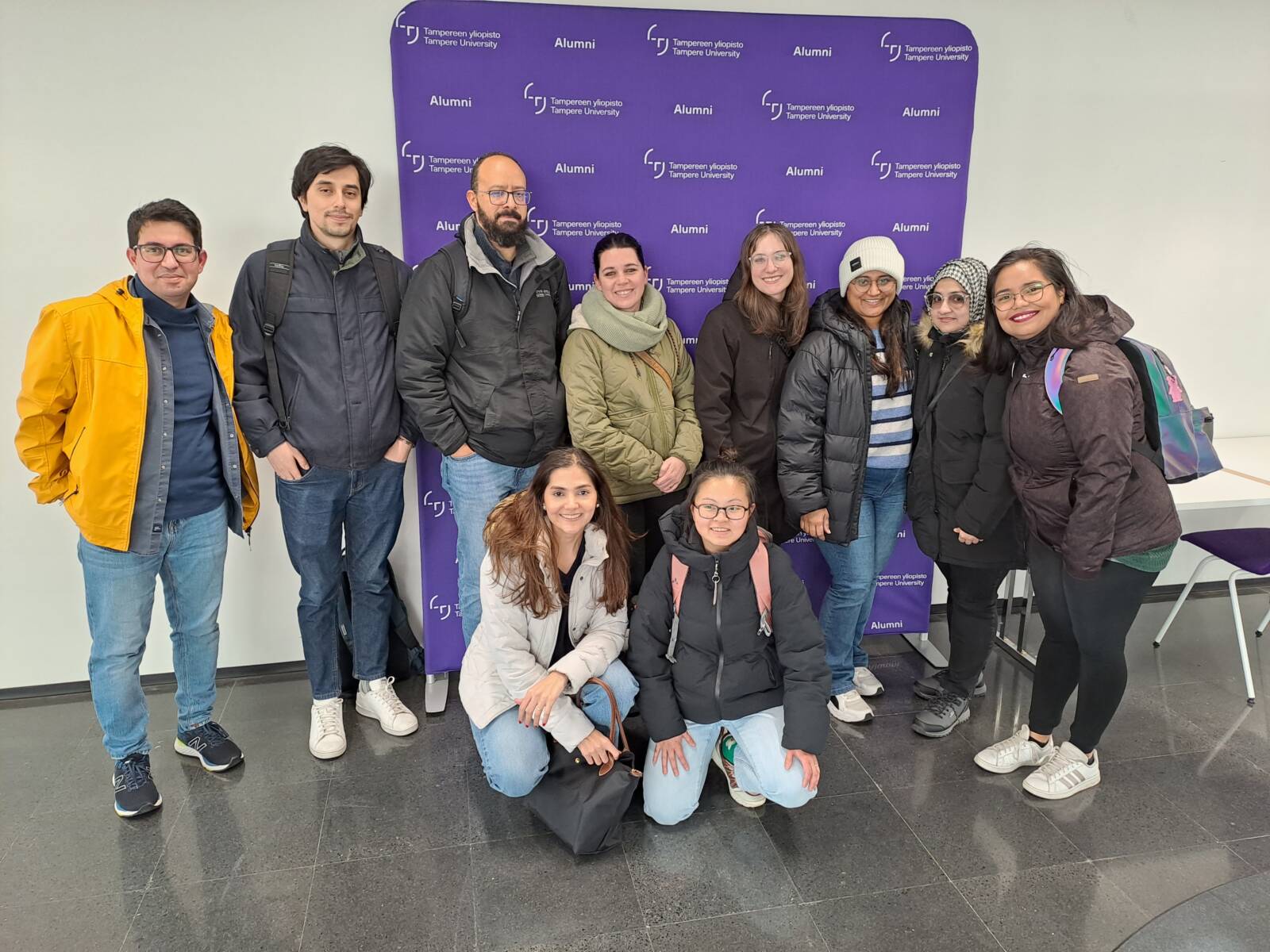 People standing in front of the Tampere University Alumni stand