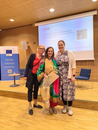 Kuvassa kolme henkilöä palkintotilaisuudessa