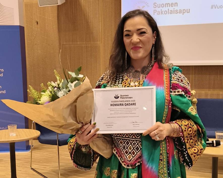 Kuvassa Homaira Qadaren kuva todistus ja kukat kädessä