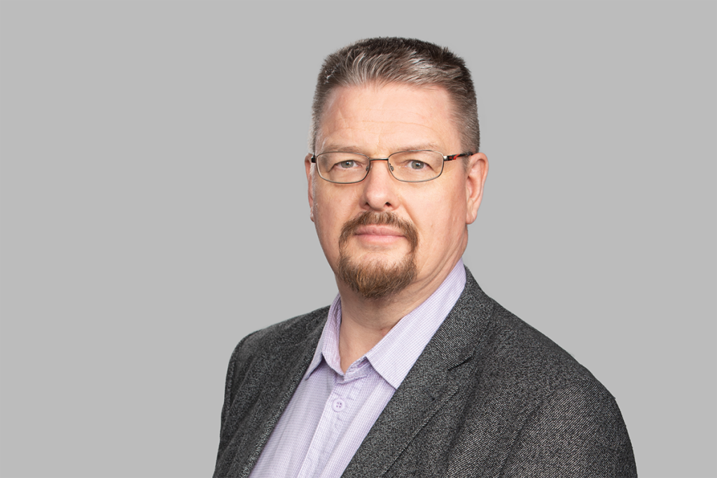 Pukuun ja kauluspaitaan pukeutunut mies. 