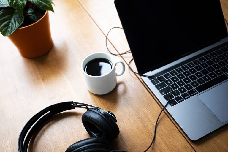 Kuvituskuva etätyöpisteestä. Pöydällä on tietokone, ruukkukasvi, kahvimuki ja sankakuulokkeet.