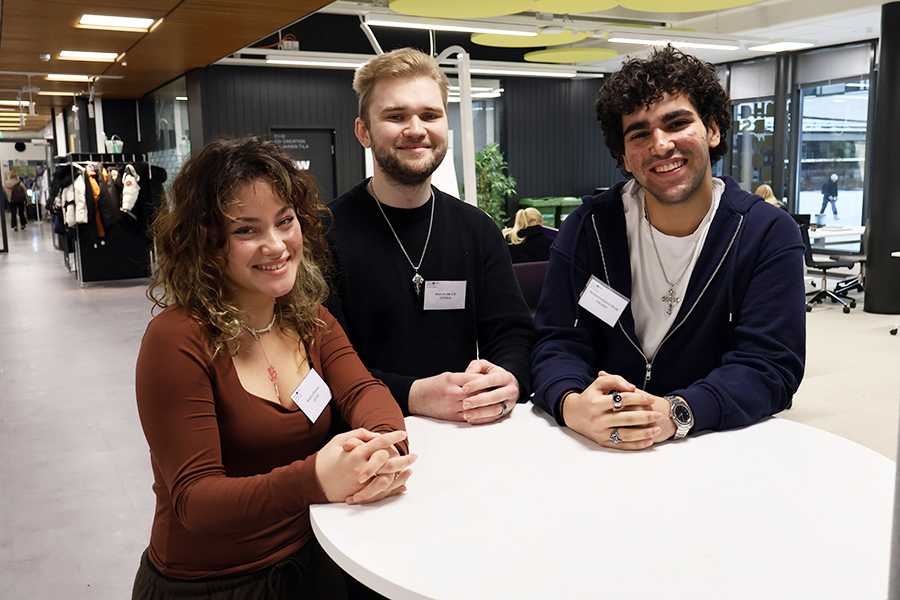 Three young adults gathered around a table and smiling.