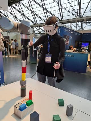 Kuvassa henkilös käyttää robottikättä XR-lasien ja ohjaimien avulla.