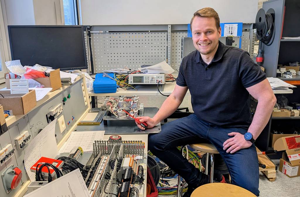 Hymyilevä mies sähkölaboratoriossa.