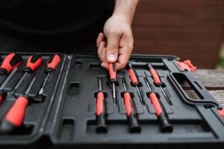 A hand reaching for a tool in a toolbox.