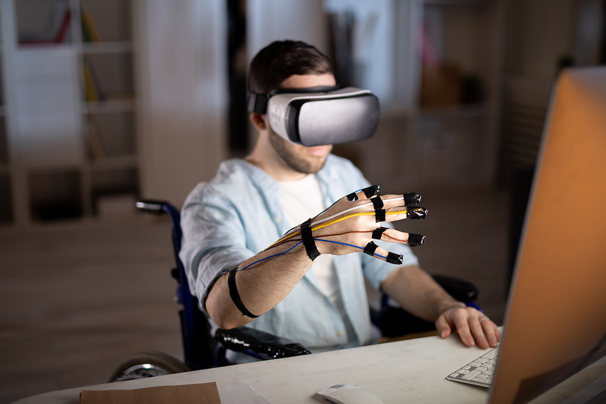 Nuori mies pöydän ääressä VR-lasit päässä ja sensori sormessa.