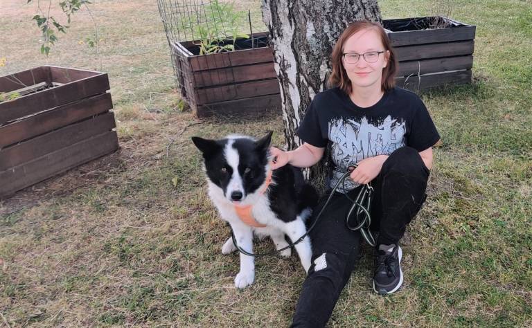 Mira Kainulainen with Karelian bear dog Cata sitting in the garden