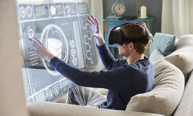 Mies istuu sohvalla VR-lasit päässä.