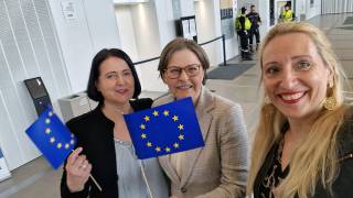 Kolme naista, joista kaksi heiluttaa pieniä EU-lippuja. 