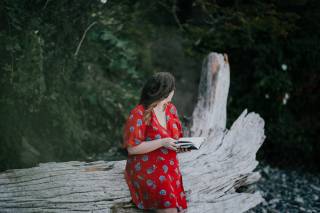 Kuvituskuva. Nainen lukee kirjaa puunrungolla.