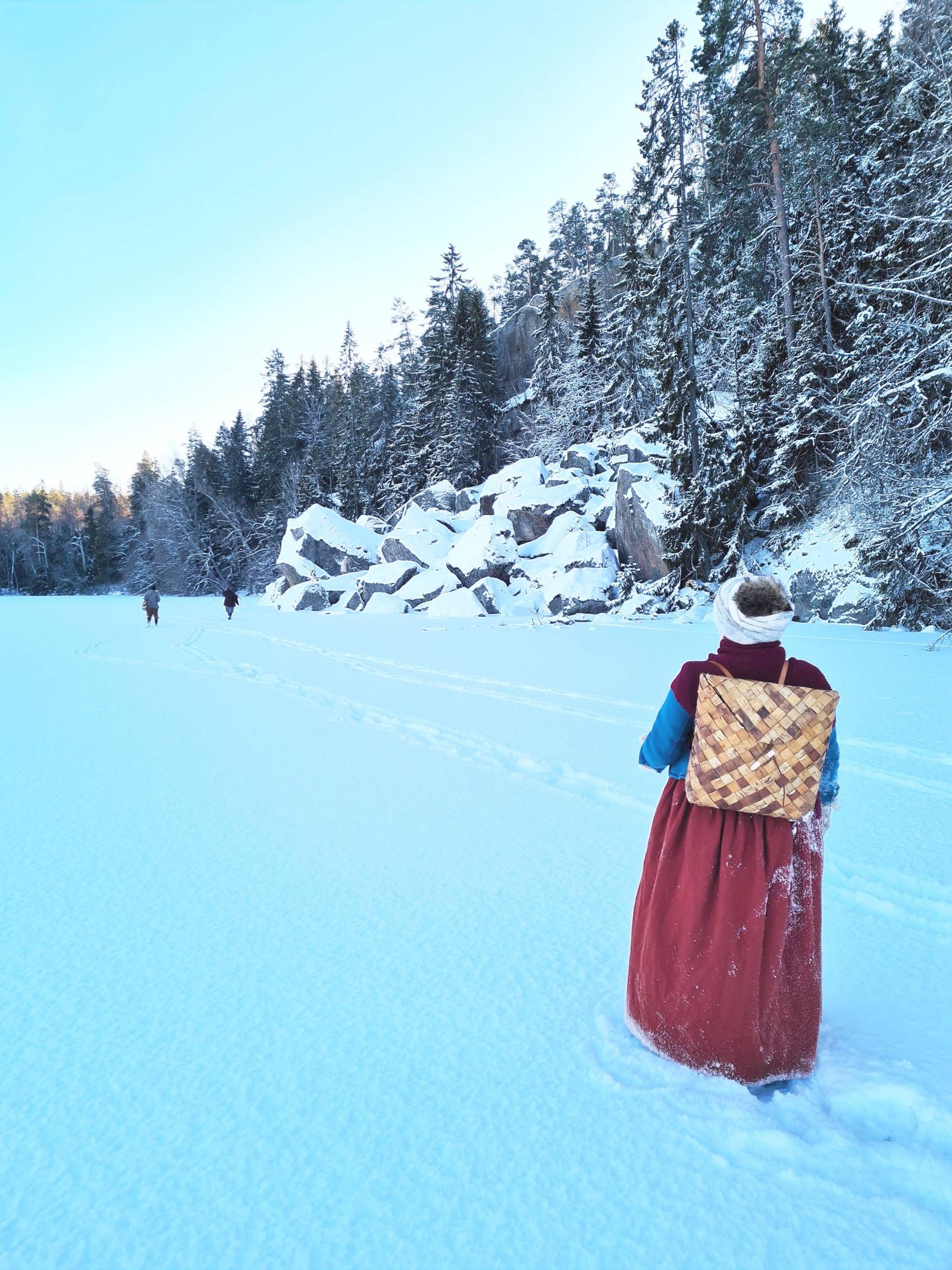 A 17th century female reenactor walking on frozen lake in Finnish winter scenery