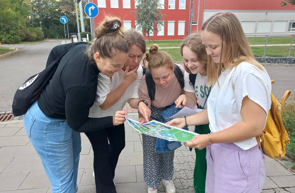 Five women reading a map in urban setting.