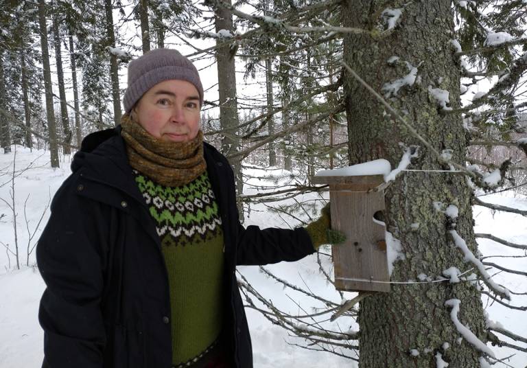 A woman dressed in winter clothes in a snowy forest.