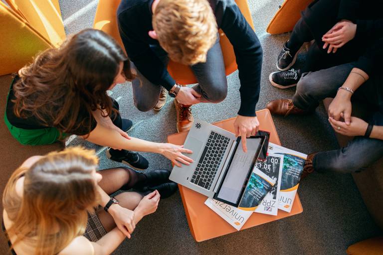 A small group of students gathered around a laptop.